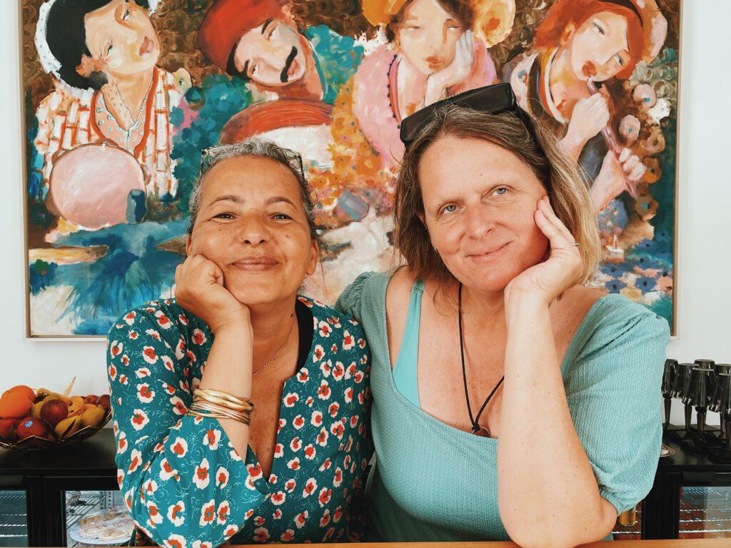 links: Myriam Maatoug, Besitzerin des Dar Oomi, Resort
rechts: Andrea Philippi, Pressereferentin, Fremdenverkehrsamt Tunesien
Porträt zweier Frauen vor einem Gemälde
